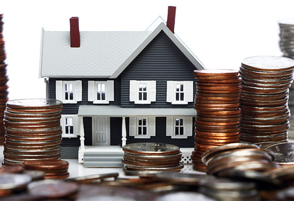 Model toy house surrounded by piles of stacked coins