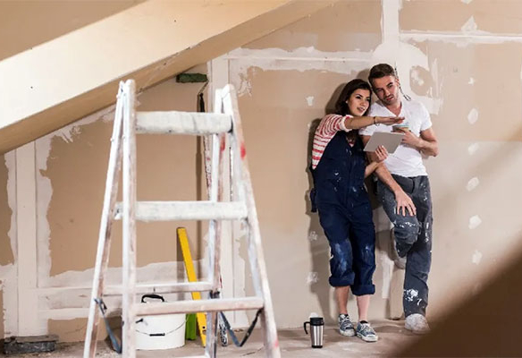 A young couple inside a newly-built home preparing to paint the walls