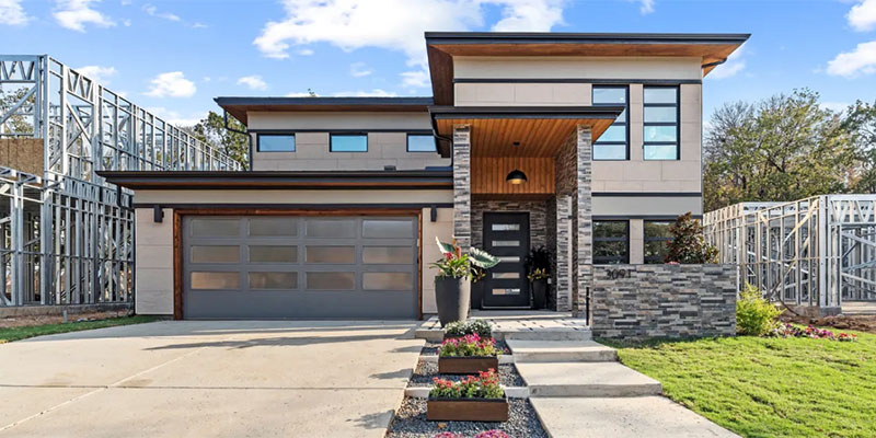 A sleek, modern house flanked by more houses under construction