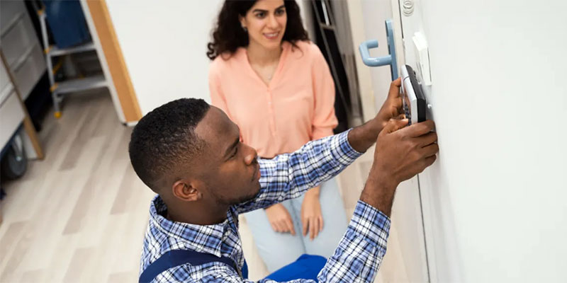 A professional technology installer at work alongside a woman in her home