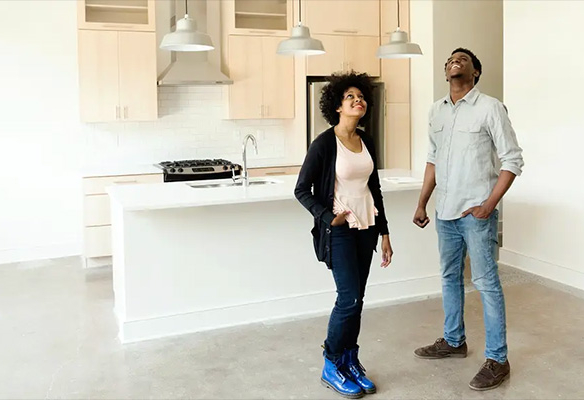 Two young home buyers standing in a new empty kitchen