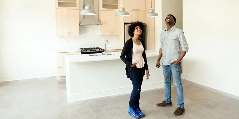 Two young home buyers standing in a new empty kitchen